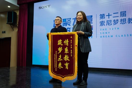 凉塘小学校副校长杨进学向索尼中国可持续发展部总监赵威回赠感谢锦旗